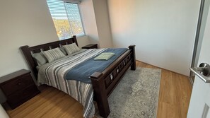 Un dormitorio con cama de madera, una mesita de noche y una puerta con manija.