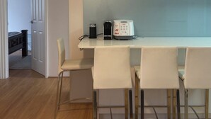 A modern kitchen with white cabinets, a coffee maker, and a ceiling fan.