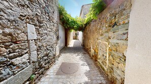 A narrow cobblestone alley with stone walls on either side, leading to a distant building. - HAUBAN - Charm & Authenticity in the Old Port (Saint-Gilles-Croix-de-Vie)