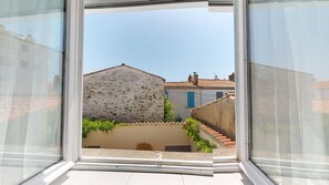 A view through a window of a building with a stone wall, a tiled roof, and a staircase leading to a lower level. - HARPON - Between the Old Port & the Historic Heart (Saint-Gilles-Croix-de-Vie)