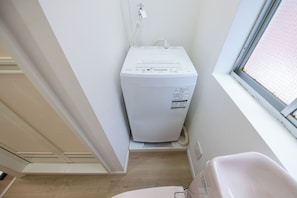 Ein Waschraum mit einer weißen Waschmaschine, einem Fenster und einem Waschbecken.