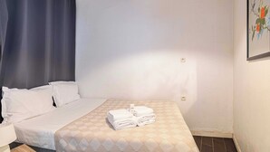 Ett hotellrum med en säng, ett nattduksbord, en lampa och en tavla på väggen.