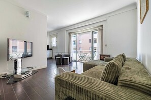 A modern living room with a flat-screen TV, a sofa, a glass coffee table, and a balcony with a view of the building. - A/C apartment with balcony- 2BDR/4P - Cannes/Beach (Cannes)