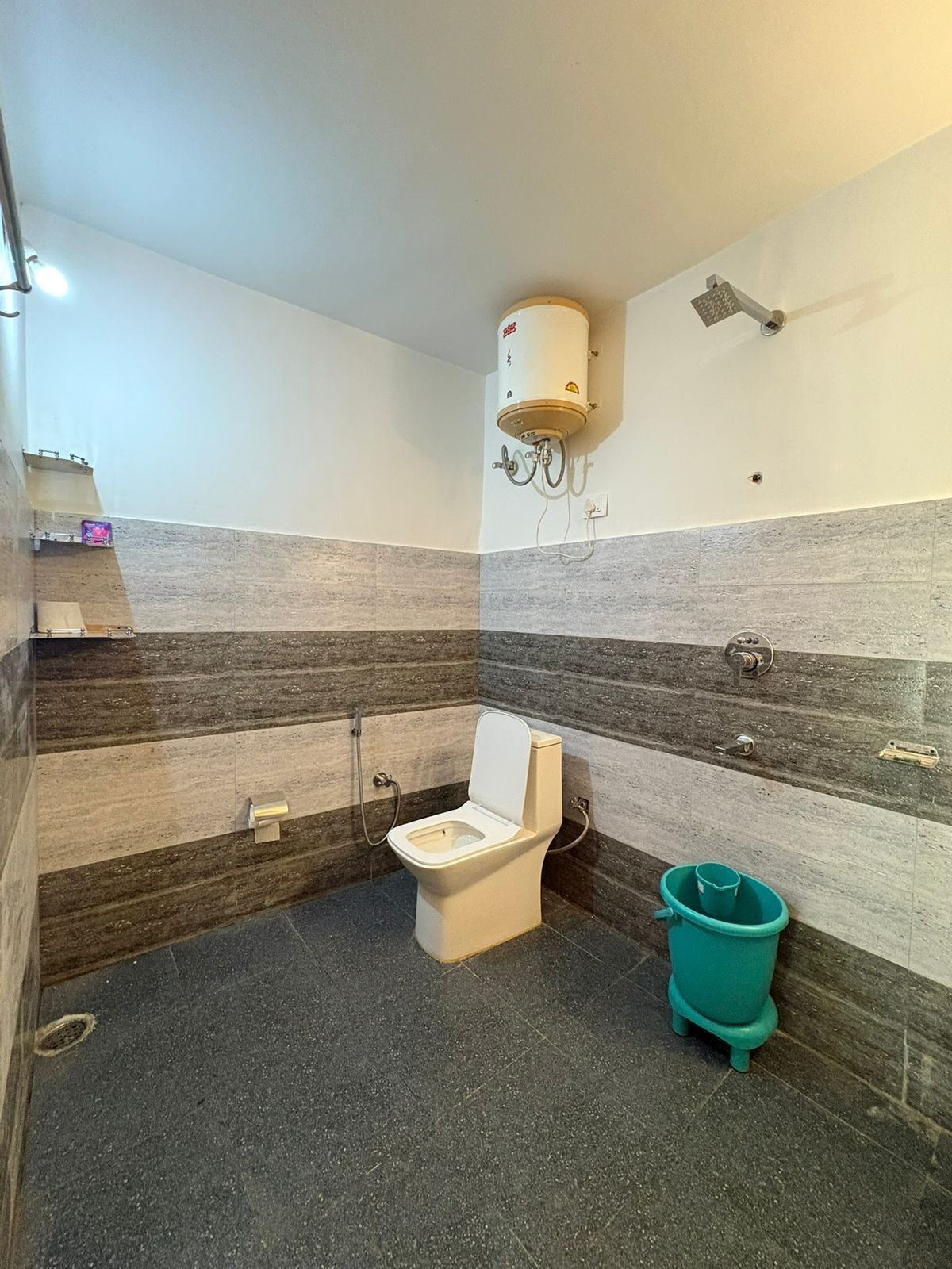 A bathroom with a toilet, a shower, and a hand dryer.