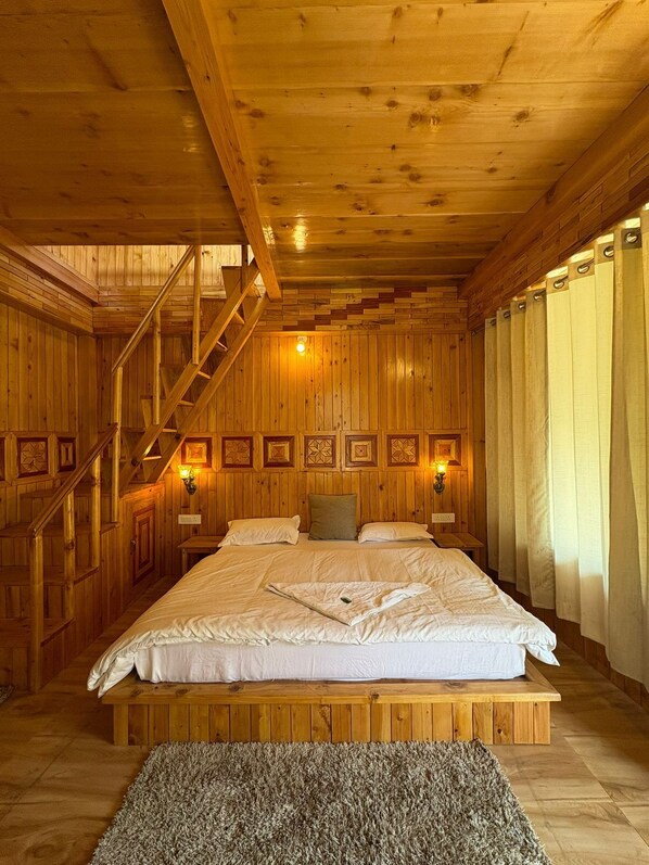 Camera da letto in una baita di legno, con un letto, una scala e luci a parete.