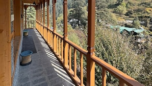 Un balcón de madera con suelo de piedra, con vista a un valle boscoso.