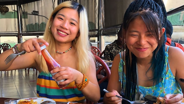 Two people dining at a restaurant with a variety of dishes on the table, including rice, meat, and fries. - Jungle Nairobi Backpackers Hostel (Nairobi)