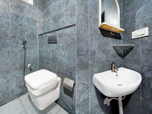 A modern bathroom with a white toilet, a sink, and a shower area. - Super Collection O Banaswadi (Bengaluru)