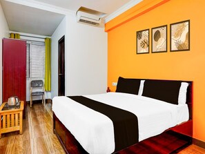 A bedroom with a bed, a wooden nightstand, a chair, an air conditioning unit, and a window with curtains. - Super Collection O Banaswadi (Bengaluru)