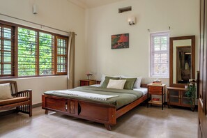 Une chambre à coucher avec un lit en bois, une table de chevet, une commode, une chaise et une fenêtre donnant sur un paysage verdoyant.