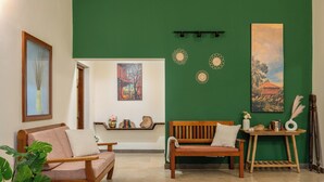 A room with two wooden sofas, a small wooden table, and a green accent wall.