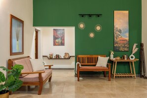 A room with two wooden sofas, a small wooden table, and a green accent wall.