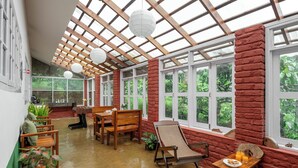 A spacious room with a wooden ceiling, large windows, and a brick wall.