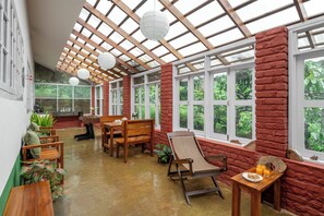Une pièce spacieuse avec un plafond en bois, de grandes fenêtres et un mur en briques.
