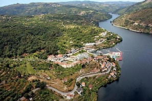An aerial view of a riverside town with buildings, roads, and greenery.