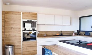 Eine moderne Küche mit integrierten Geräten, weißen Schränken und einer Wand in Holzoptik.