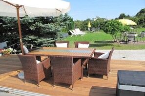 A deck with a table and chairs, surrounded by greenery and umbrellas. - Small Island Double Room - Plus (Ostseebad Heringsdorf)