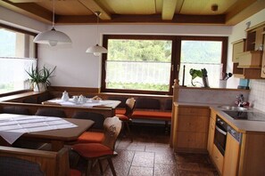 A compact kitchen with a dining area, wooden cabinets, and a window with a view of greenery. - Holiday home in Krimml with swimming pool (Krimml)