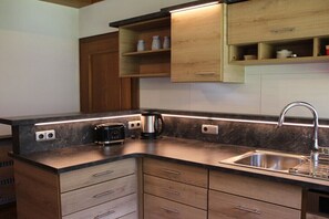 A modern kitchen with wooden cabinets, a stainless steel sink, and under-cabinet lighting. - Holiday home in Krimml with swimming pool (Krimml)