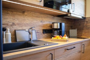 A modern kitchen with a wooden backsplash, stainless steel appliances, and a fruit bowl on the countertop. - Apartment in Mittelberg with swimming pool (Mittelberg)