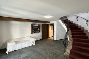 A staircase with a red carpet, a white sofa with a striped cover, and a wooden shelf with books. - Apartment in Mittelberg with swimming pool (Mittelberg)