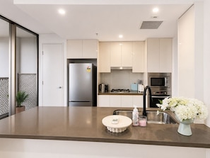 A modern kitchen with stainless steel appliances, a central island with a sink, and a decorative vase.