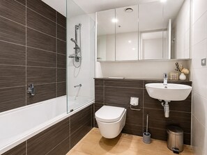 A modern bathroom with a bathtub, toilet, and sink.