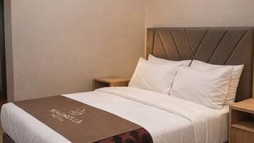 Ein Hotelzimmer mit Bett, Nachttisch, Holzboden und Klimaanlage.