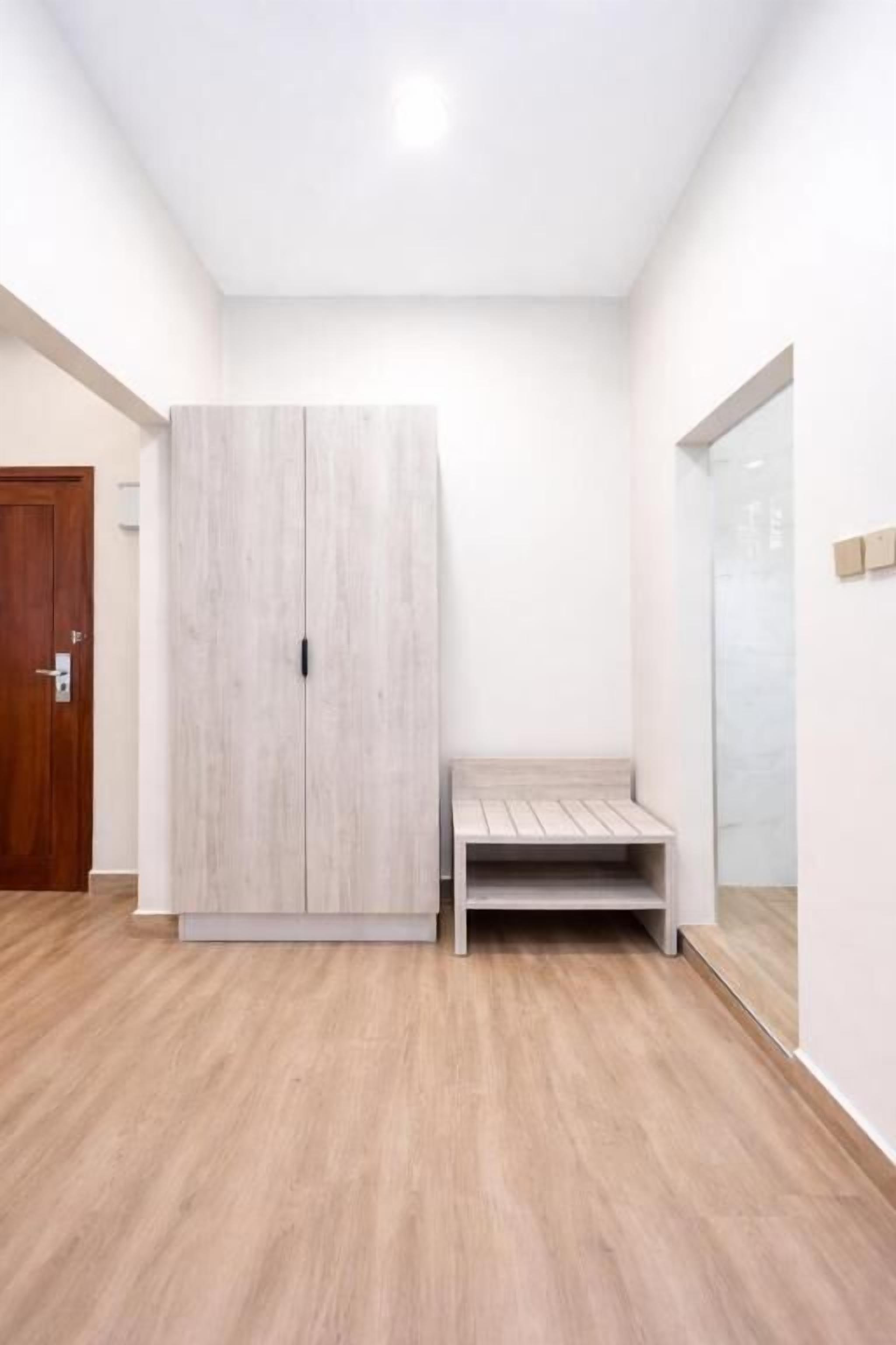 A room with a wardrobe, a bench, and a door.