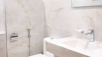 A modern bathroom with a shower, toilet, sink, and a towel rack.