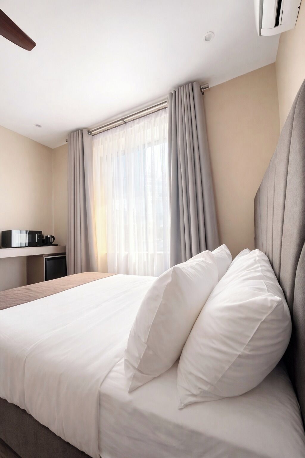 Una habitación de hotel con cama, escritorio y ventana con cortinas.