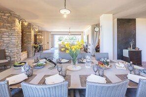 A dining area with wicker furniture, a stone wall, and a view of the outdoors. - Villa in Canale with 5 bedrooms sleeps 14 (Canale)