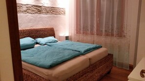 A bed with a woven headboard, a blue blanket, and a beige mattress. - Inviting Apartment With Pool Near the Beach (Lignano Sabbiadoro)