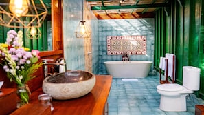 Un baño con una bañera independiente, un inodoro, un lavabo grande y un espejo con un marco decorativo.