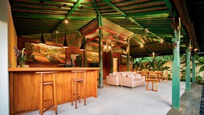 A spacious indoor area with a wooden bar, seating, and a mural on the wall. - Juwel Villa Ubud (Ubud)
