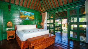 A room with a bed, wooden furniture, a painting, and a view through large windows. - Juwel Villa Ubud (Ubud)