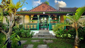 A traditional house with a tiled roof, a front porch, and a garden with tropical plants. - Juwel Villa Ubud (Ubud)