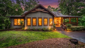 Une maison en bois avec un porche, de grandes fenêtres et une pelouse bien entretenue.
