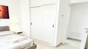 A bedroom with a bed, a bench, a wardrobe, and an air conditioning unit. - Your vacation in Otranto a stone's throw from the sea and the historic center (Otranto)