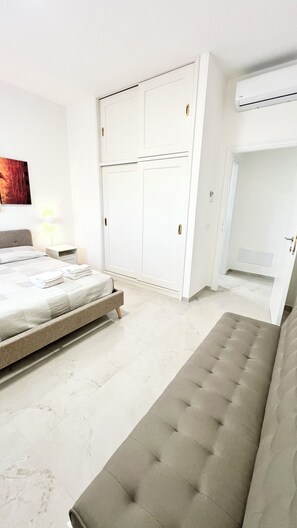 Ein Schlafzimmer mit Bett, einer Sitzbank, einem Kleiderschrank und einer Klimaanlage.