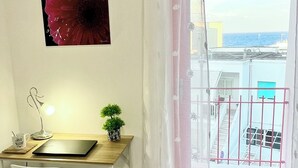 A room with a desk, chair, potted plant, and a large window with a view of the sea. - Your vacation in Otranto a stone's throw from the sea and the historic center (Otranto)