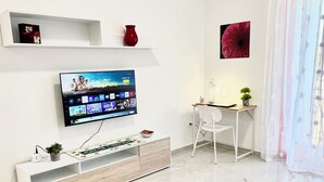 A modern living room with a flat-screen TV, a white sofa, a gaming table, and a decorative rug. - Your vacation in Otranto a stone's throw from the sea and the historic center (Otranto)