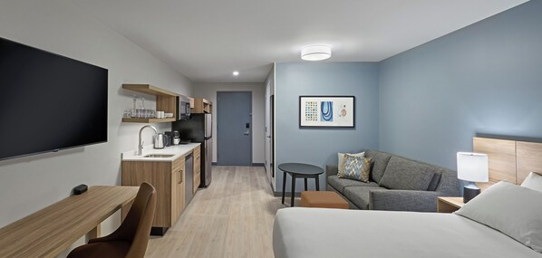 A hotel room with a bed, a desk, a kitchenette, a TV, and a framed artwork on the wall. - Hyatt Studios Superior/Boulder (Superior)