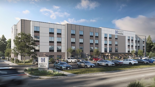 A multi-story hotel with a modern design, featuring a parking lot with several cars.