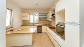 A modern kitchen with a central island, built-in oven, and stainless steel appliances. - Bonvie Apartments in Center B9 (Novalja)