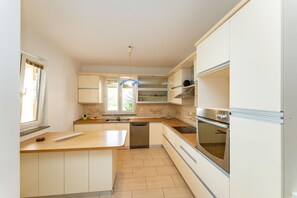 A modern kitchen with a central island, built-in oven, and stainless steel appliances. - Bonvie Apartments in Center B9 (Novalja)