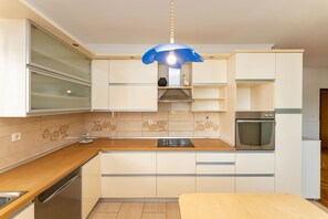 A modern kitchen with a built-in oven, a dishwasher, and a blue pendant light. - Bonvie Apartments in Center B9 (Novalja)