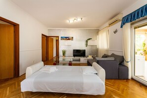 A hotel room with a bed, a sofa, a TV, and a dining table. - Bonvie Apartments in Center B9 (Novalja)