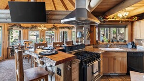 Une cuisine rustique dotée d’un grand îlot central, de meubles en bois et d’un plan de travail en pierre.