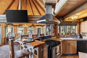 Une cuisine rustique dotée d’un grand îlot central, de meubles en bois et d’un plan de travail en pierre.
